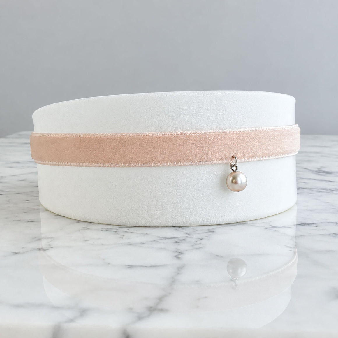 Model wearing a blush-pink velvet choker with a small pearl-style pendant