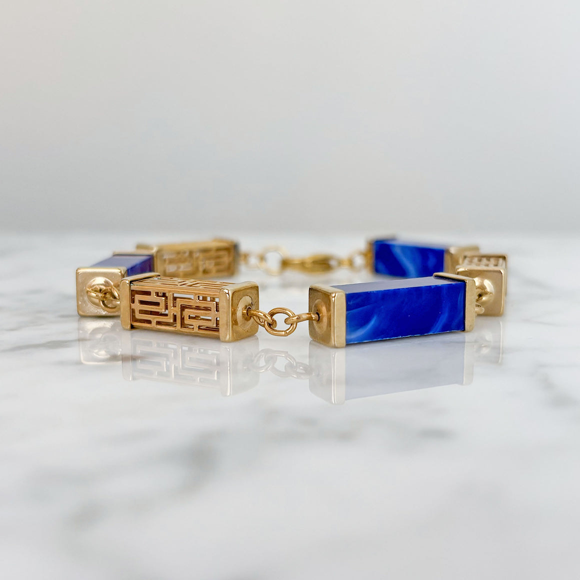 Vintage gold-tone filigree and blue marbled resin link bracelet worn on a wrist