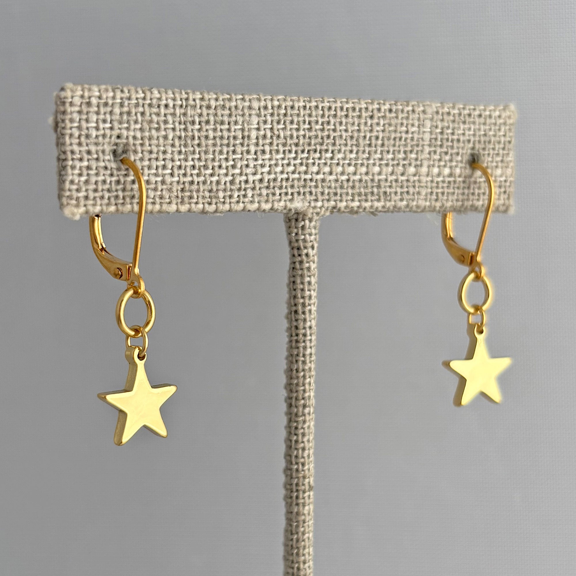 18K gold star drop earrings with lever back wires suspended from linen t bar