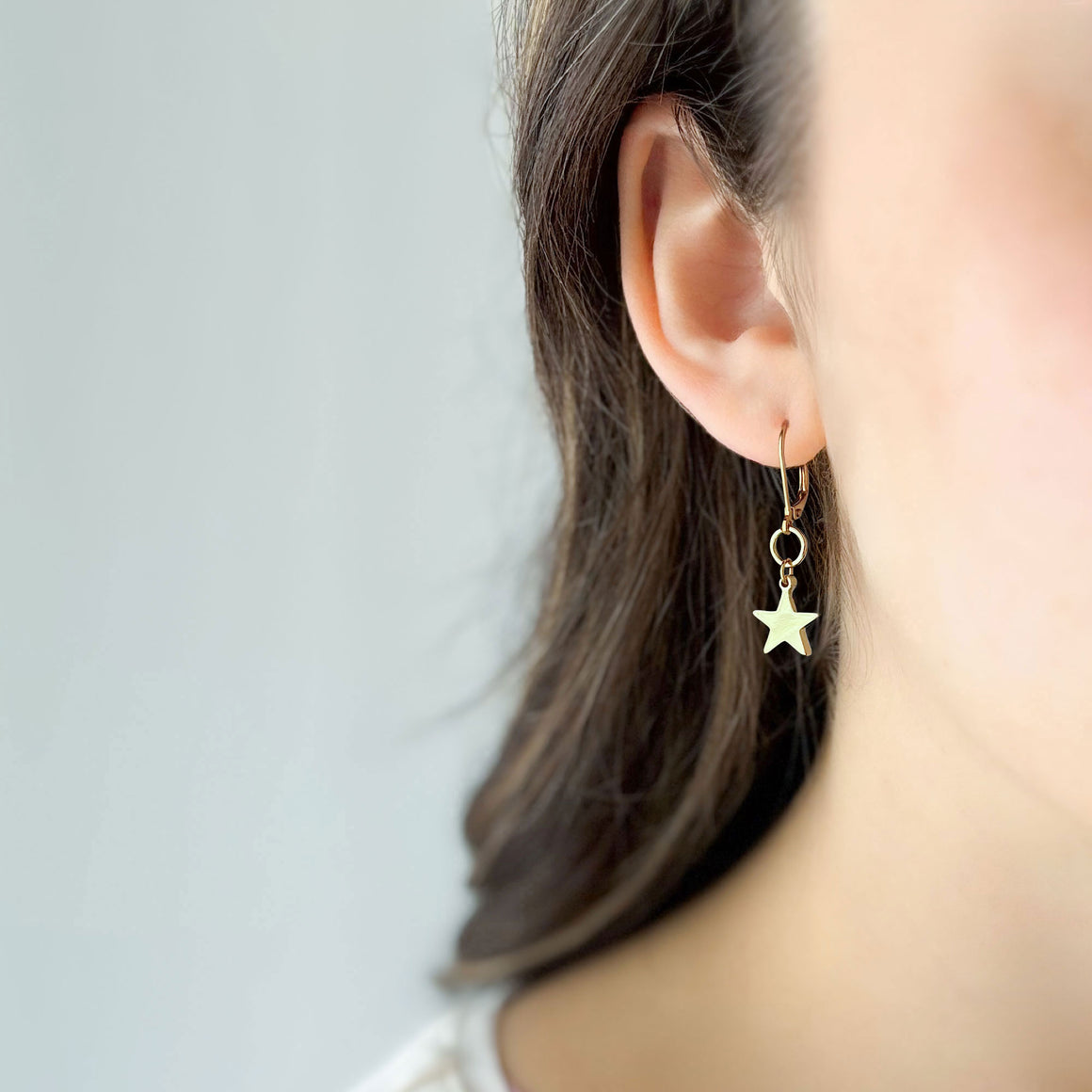 18K gold star drop earrings with lever back wires suspended from linen t bar