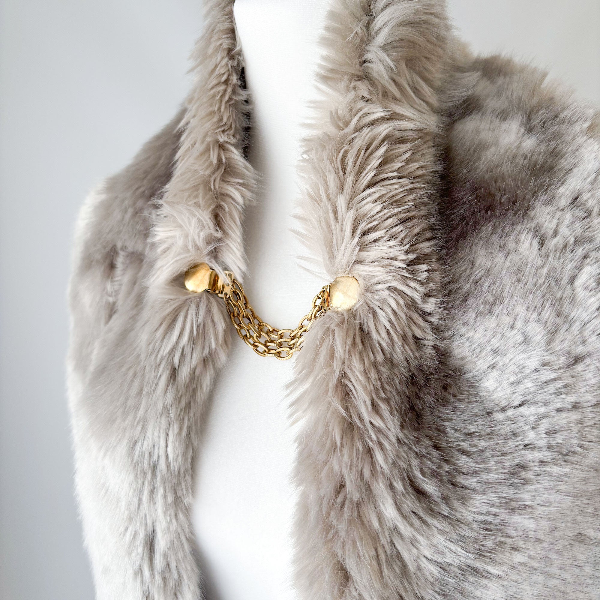 Gold-tone cardigan clips with round discs and ridged chains fastening a grey fur collar