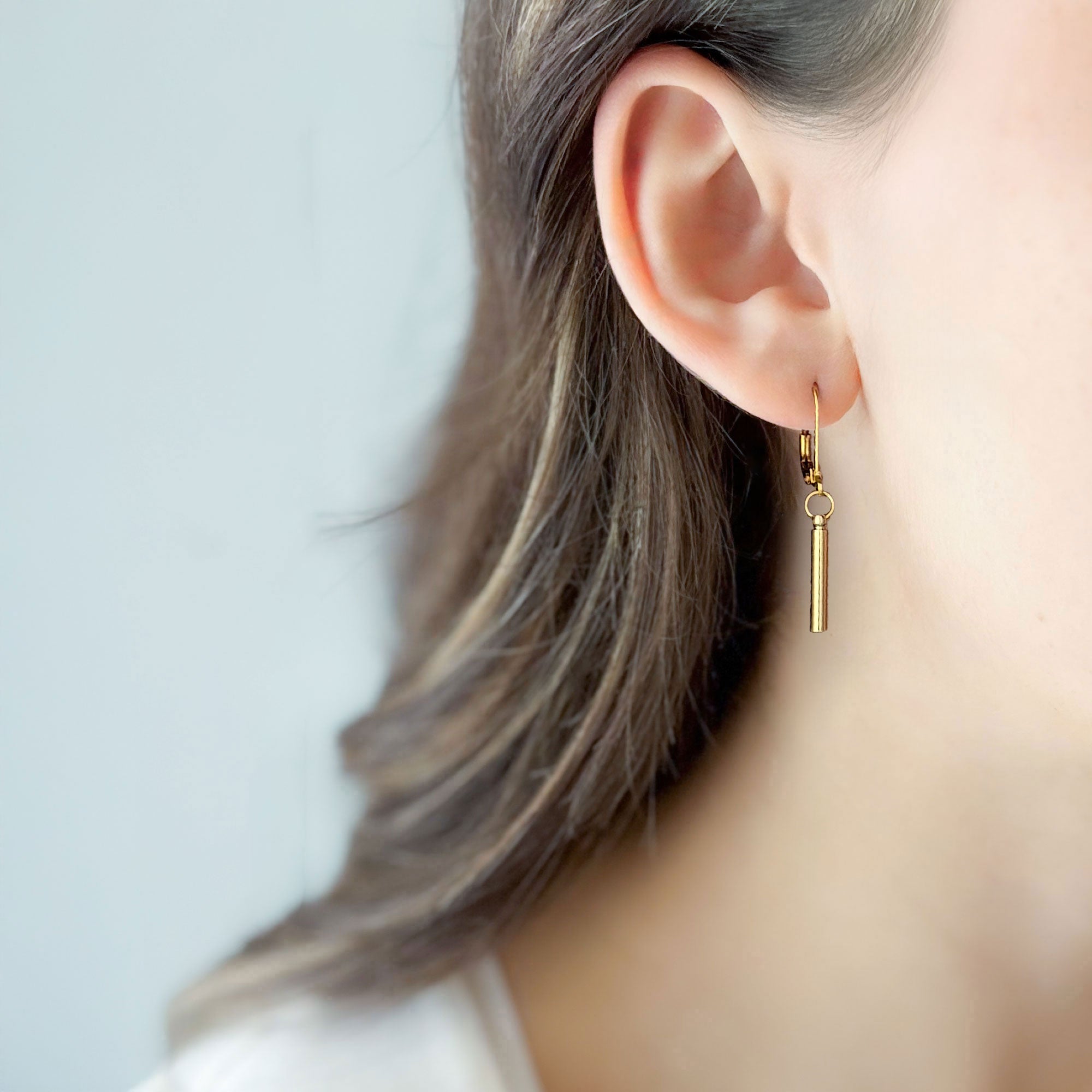 Woman wearing minimalist 18K gold-plated bar drop earrings