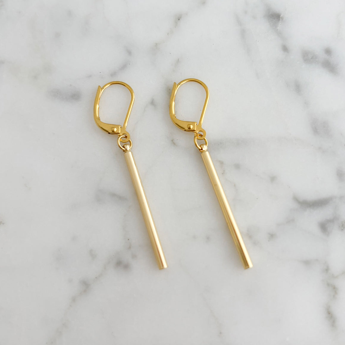 Woman wearing minimalist 18K gold-plated bar drop earrings