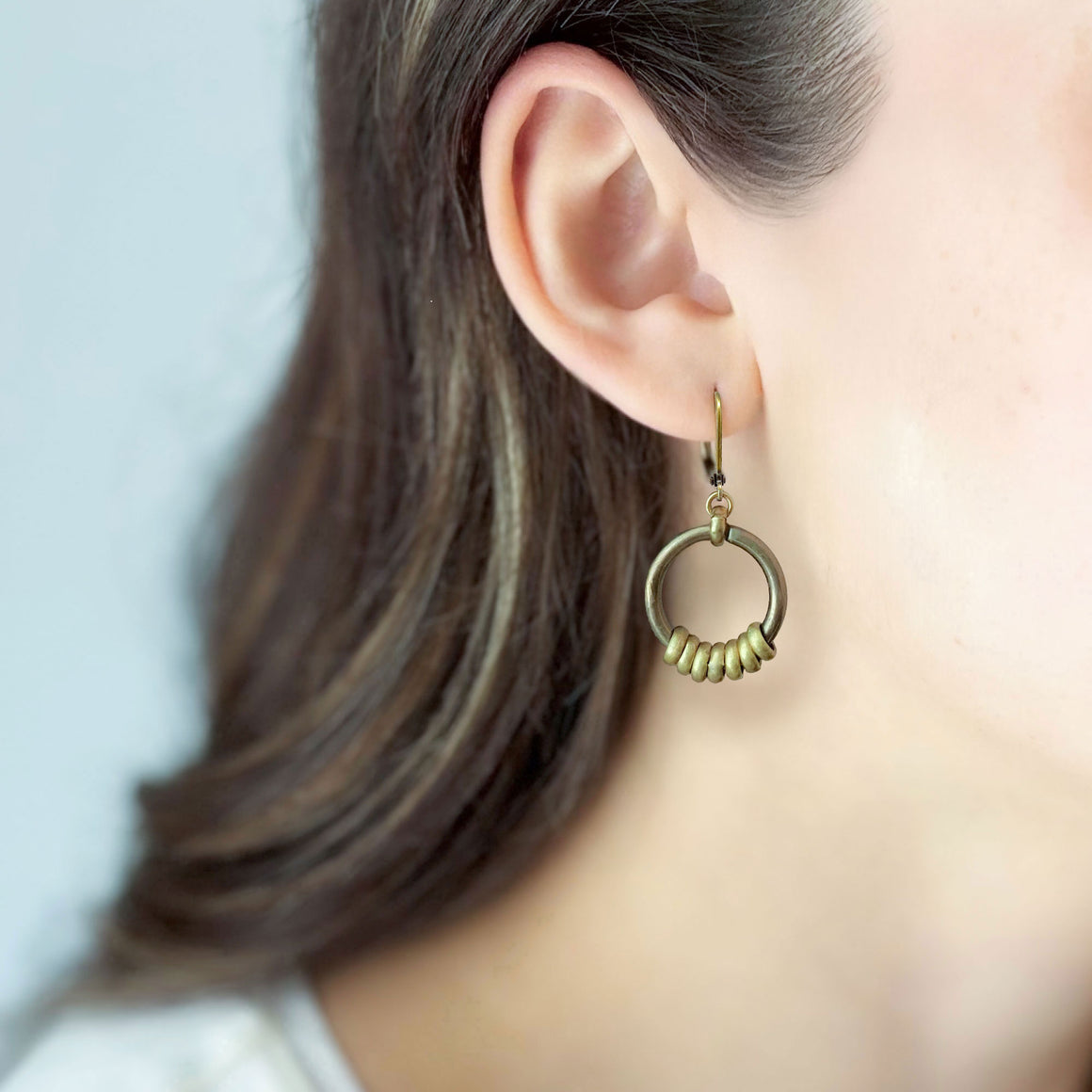 Oxidized brass-tone circular hoop earrings displayed on a linen t bar display