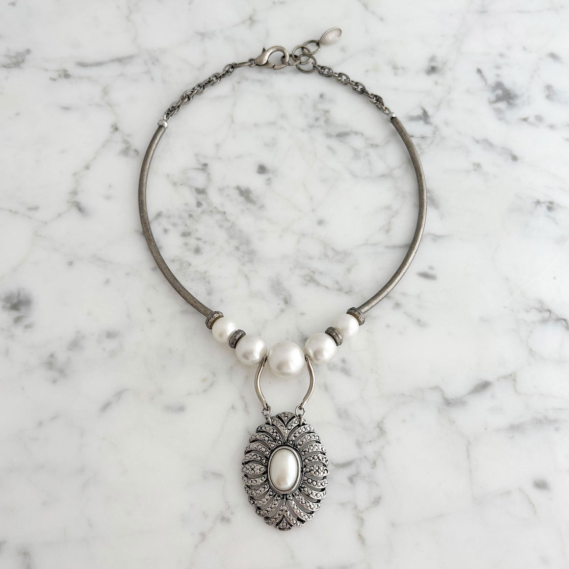 Woman wearing a pearl and marcasite pendant necklace with oxidized silver-tone details