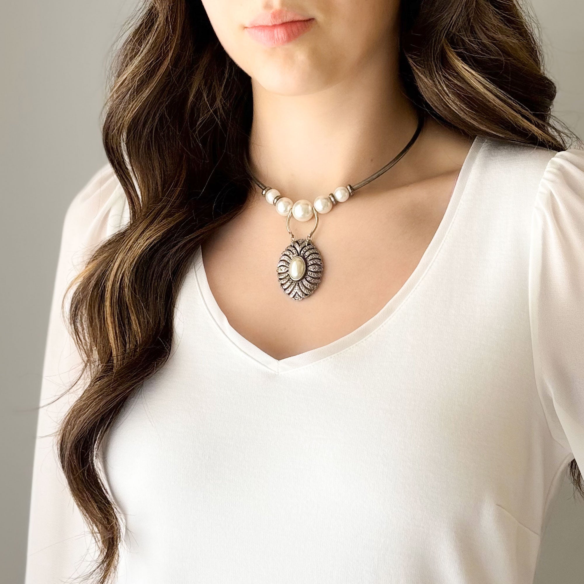 Woman wearing a pearl and marcasite pendant necklace with oxidized silver-tone details
