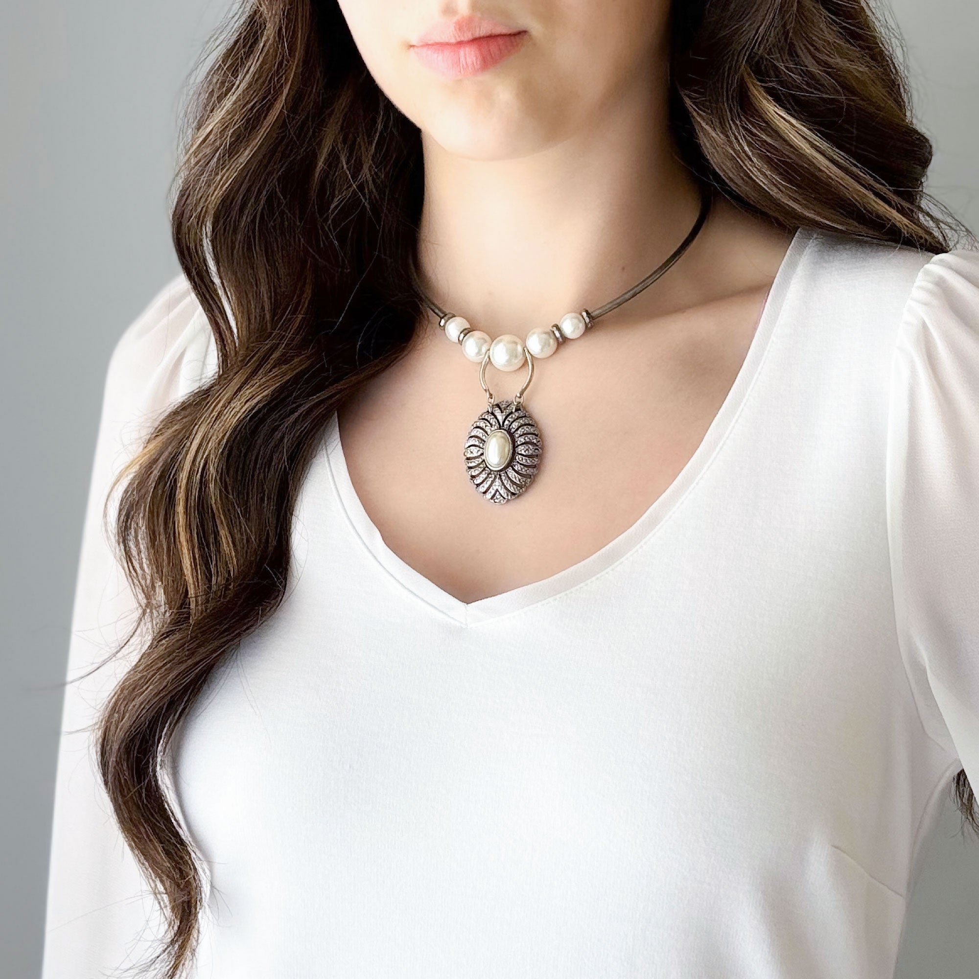 Woman wearing a pearl and marcasite pendant necklace with oxidized silver-tone details