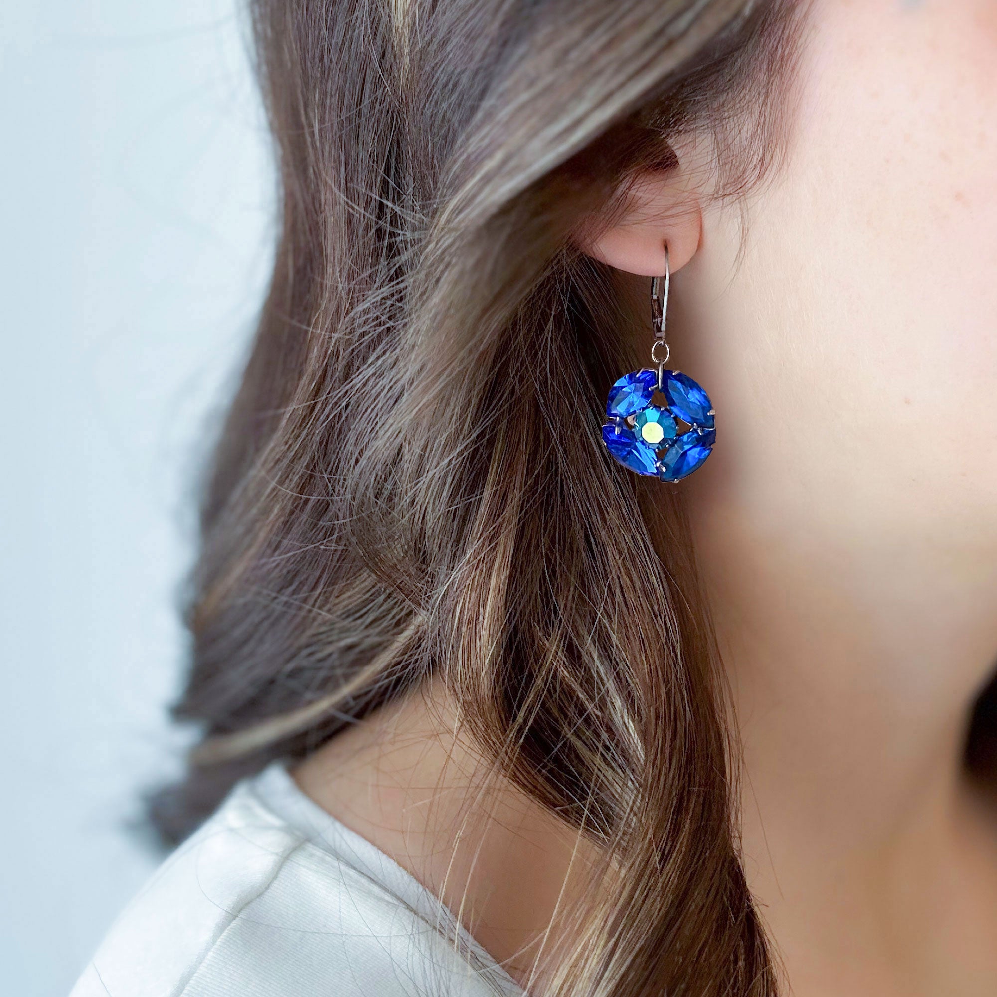 Sapphire blue crystal drop earring with iridescent accents worn by a model with dark hair