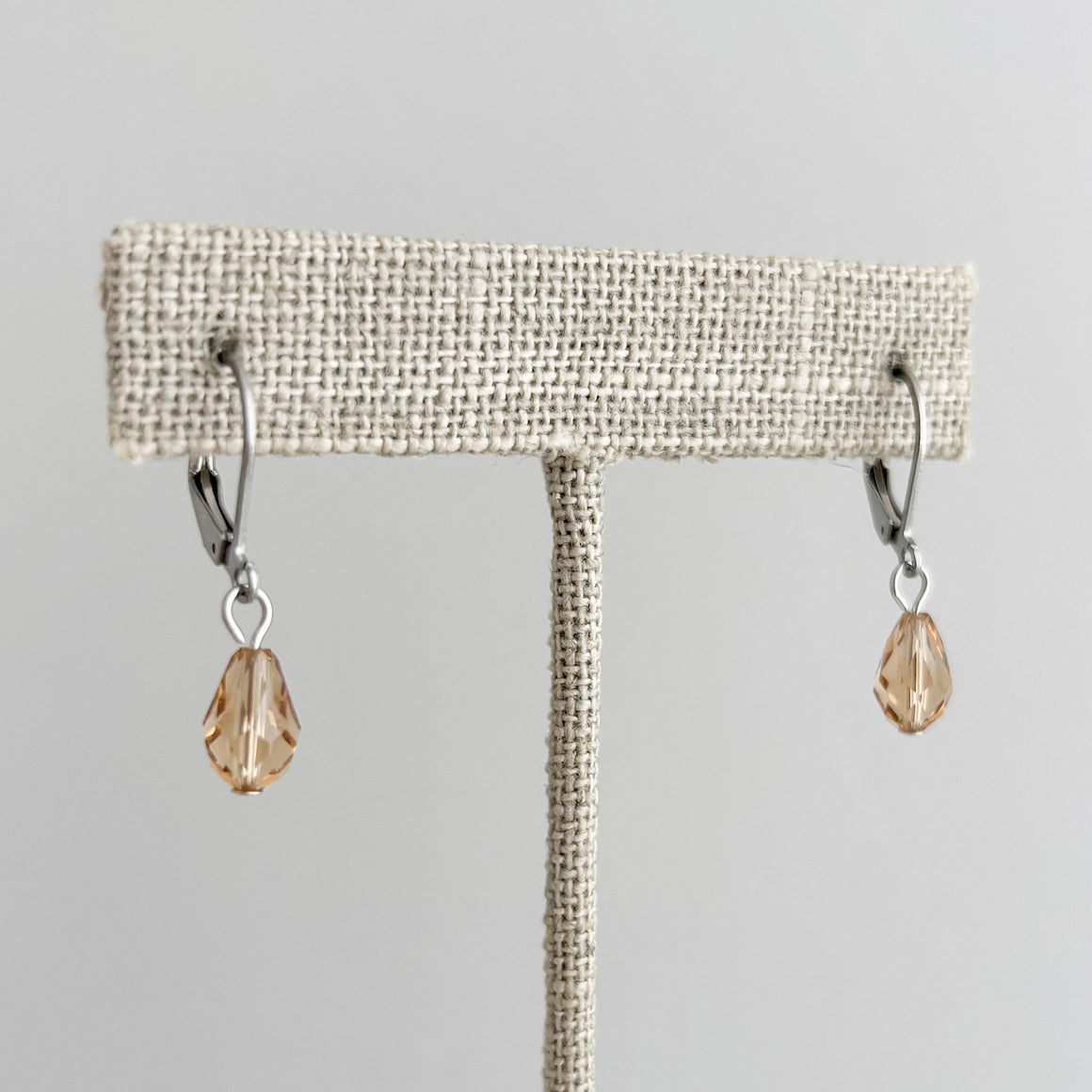 Dainty faceted topaz crystal drop earrings worn on a model