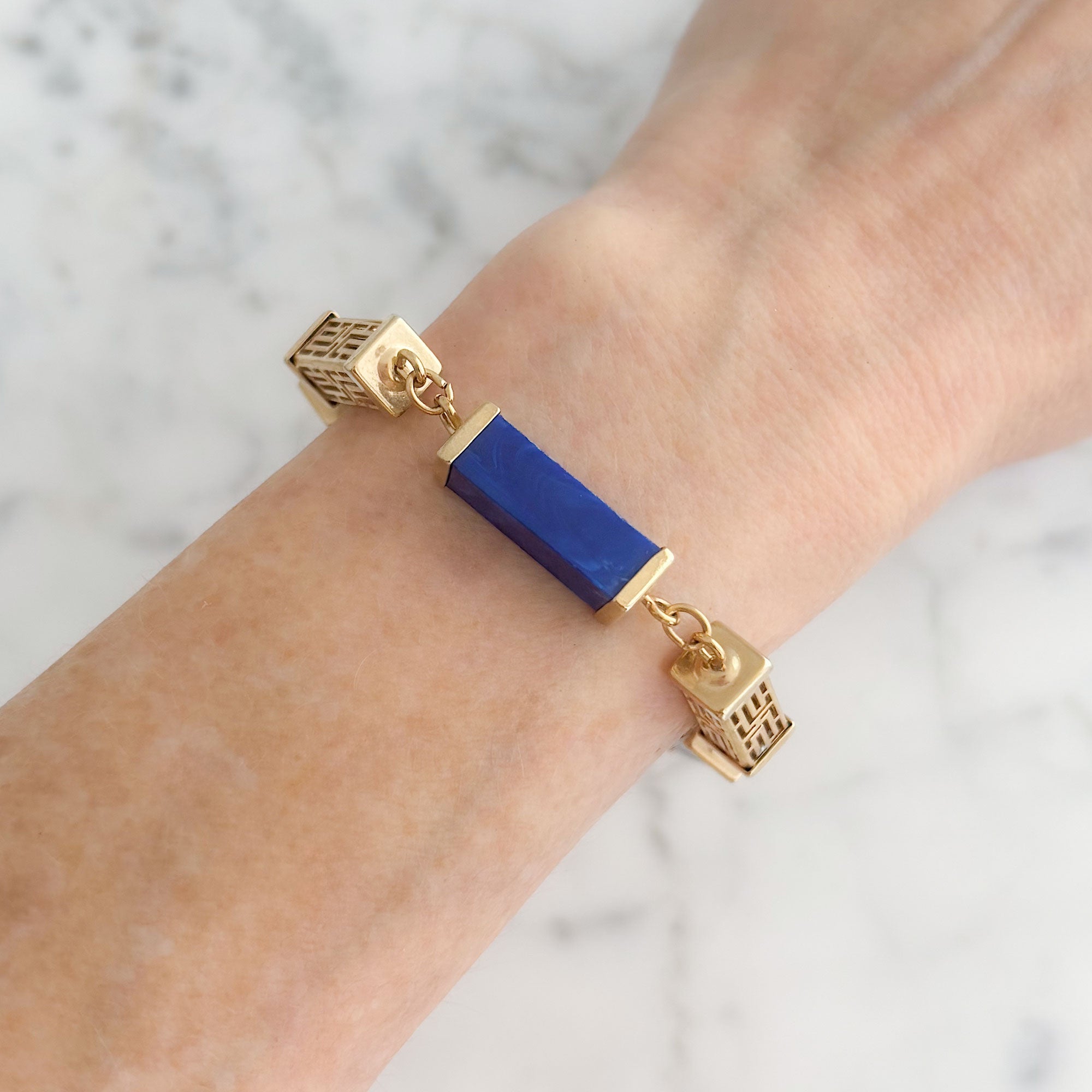 Vintage gold-tone filigree and blue marbled resin link bracelet worn on a wrist