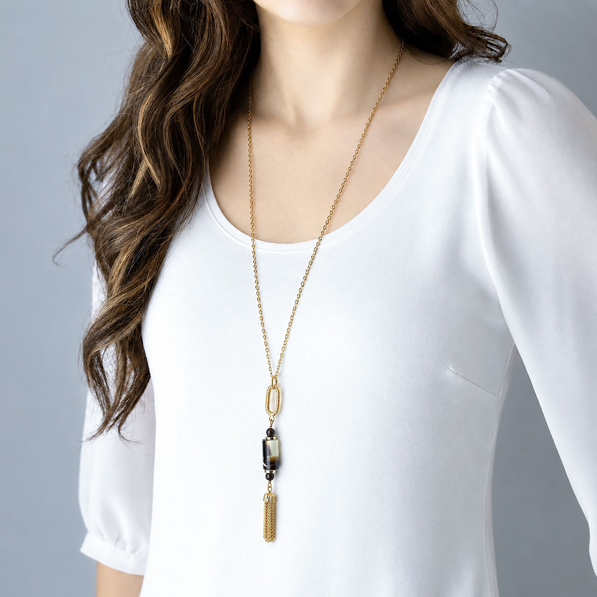 Close-up of a marbled vintage pendant with brown glass pearls and a gold-tone chain tassel