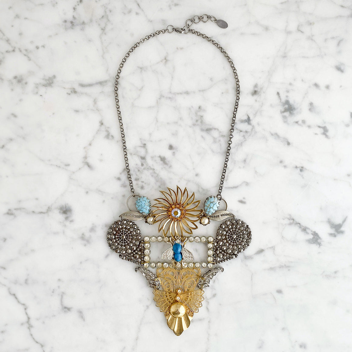 Model wearing an elaborate statement necklace featuring vintage bee motifs, floral details, rhinestones and mixed-metal components