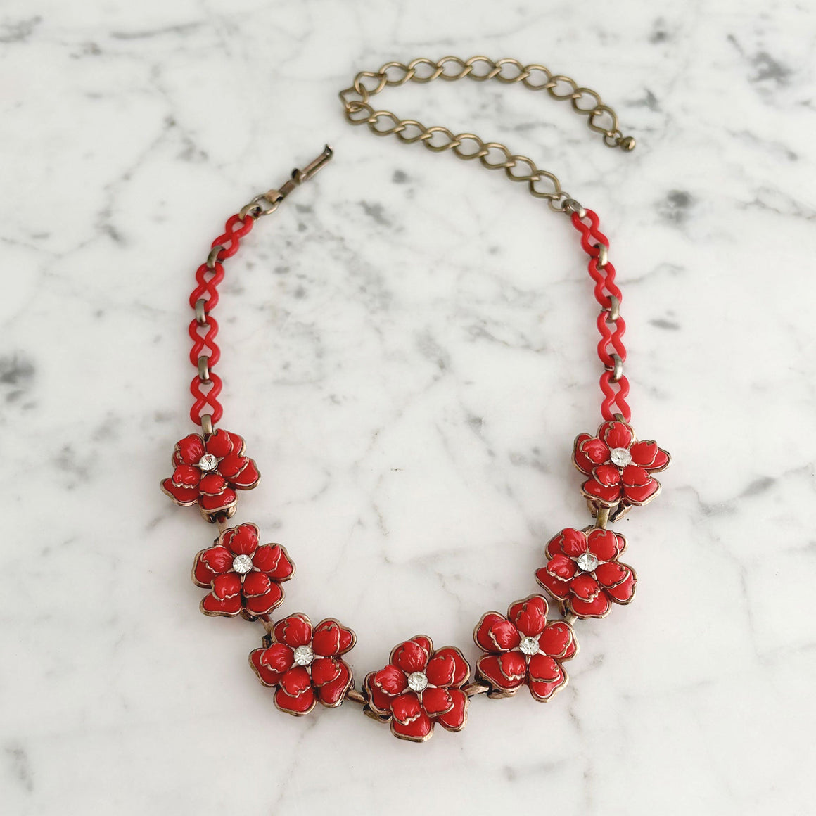 Woman wearing a vintage red floral necklace at princess length