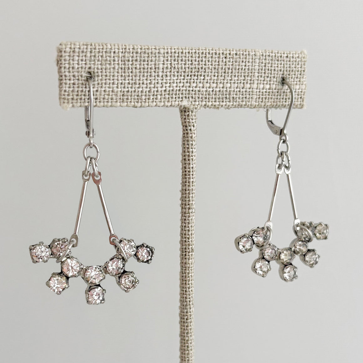 Woman wearing vintage silver rhinestone starburst dangle earrings
