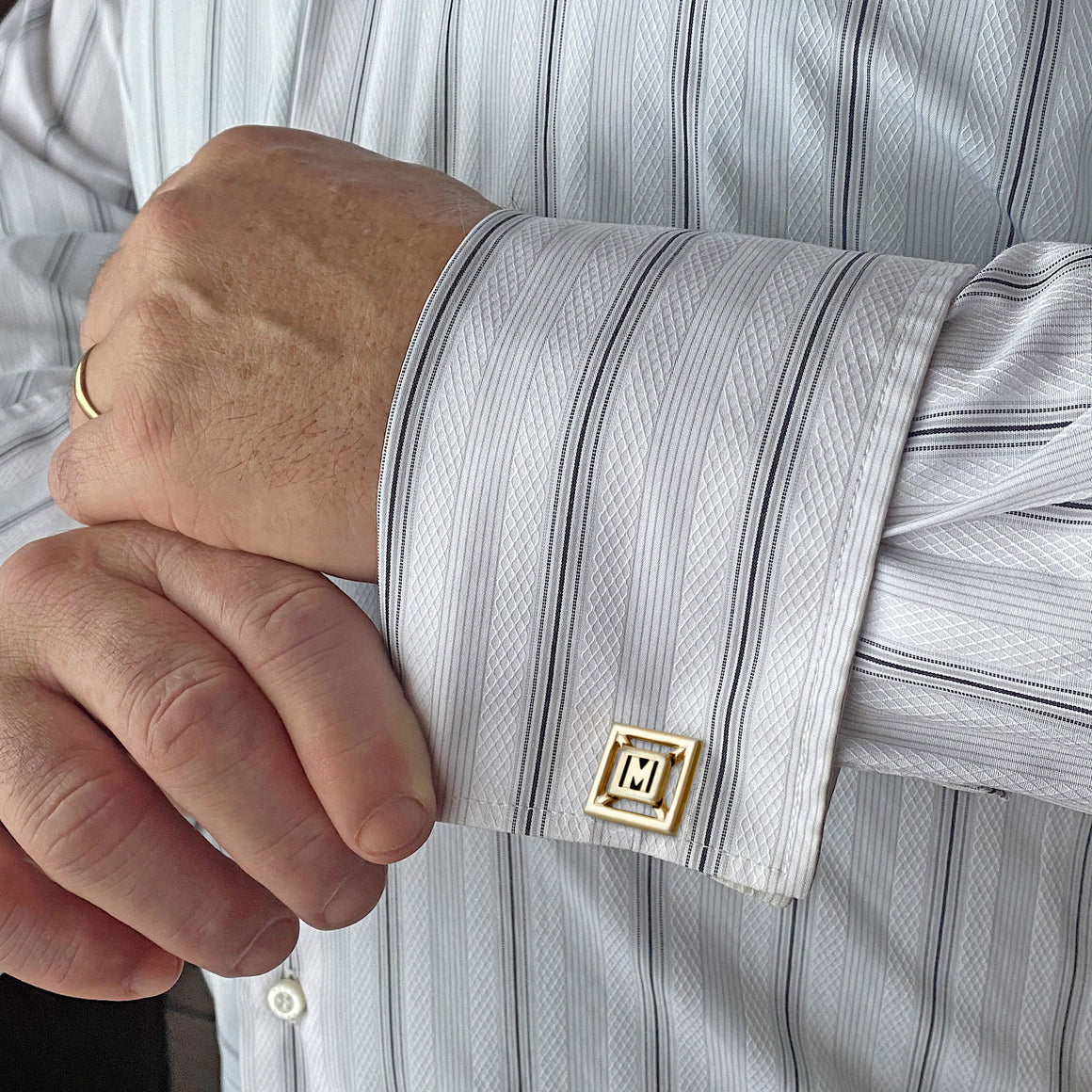 Vintage Swank gold-tone cufflinks with black enamel M monogram displayed on marble