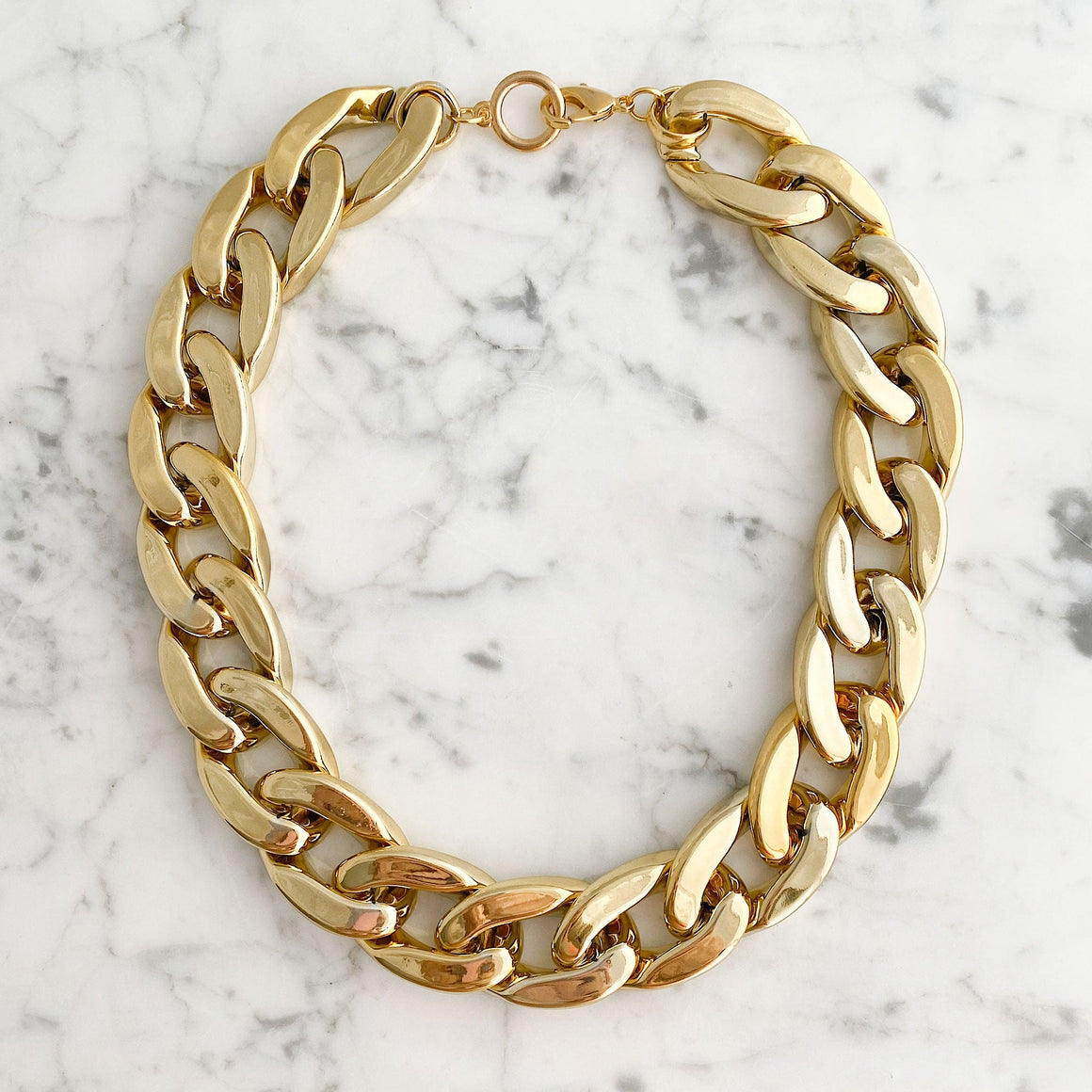 Woman wearing a lightweight gold-tone chunky chain necklace with oversized curb links